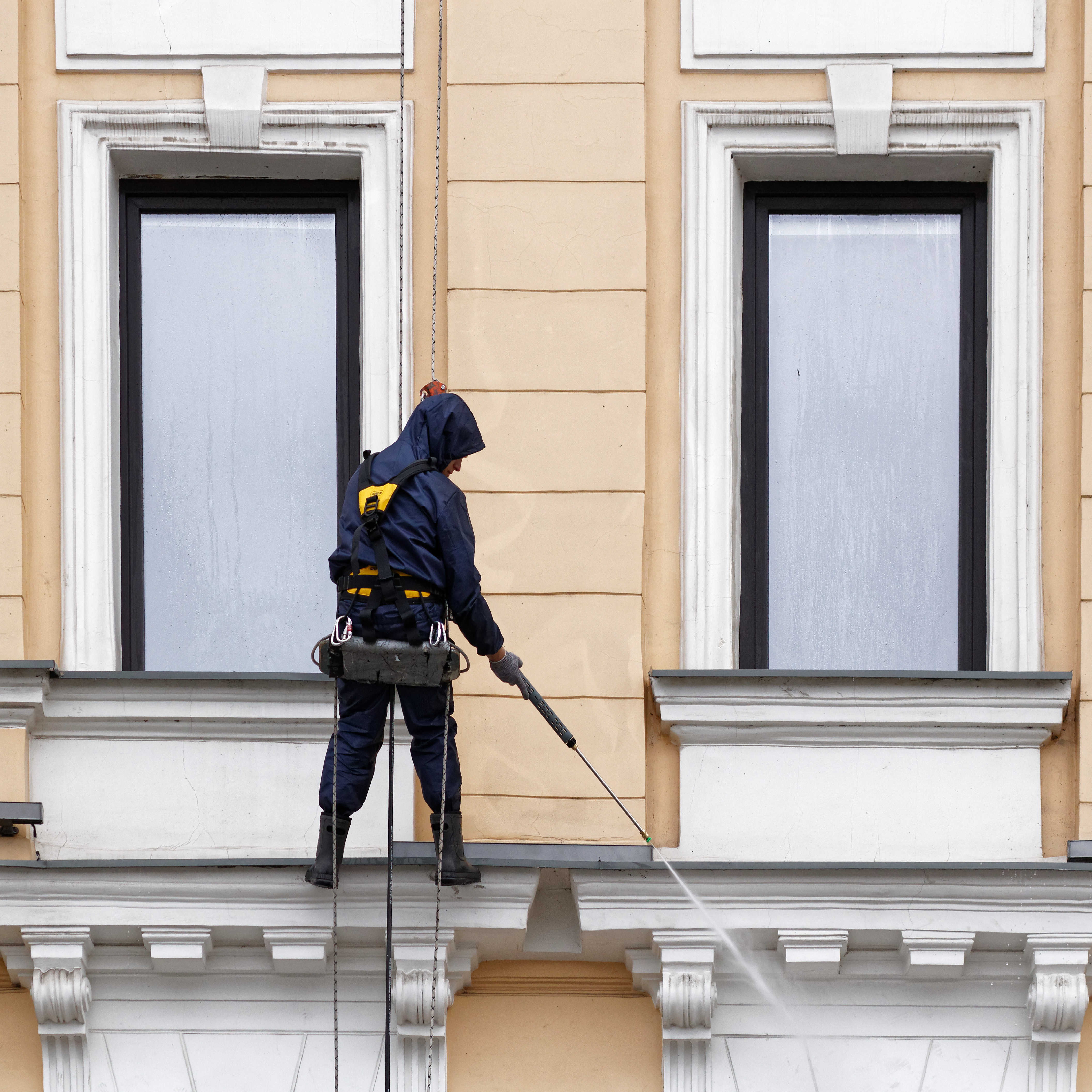 Technicien professionnel nettoyant une façade en corde d'accès