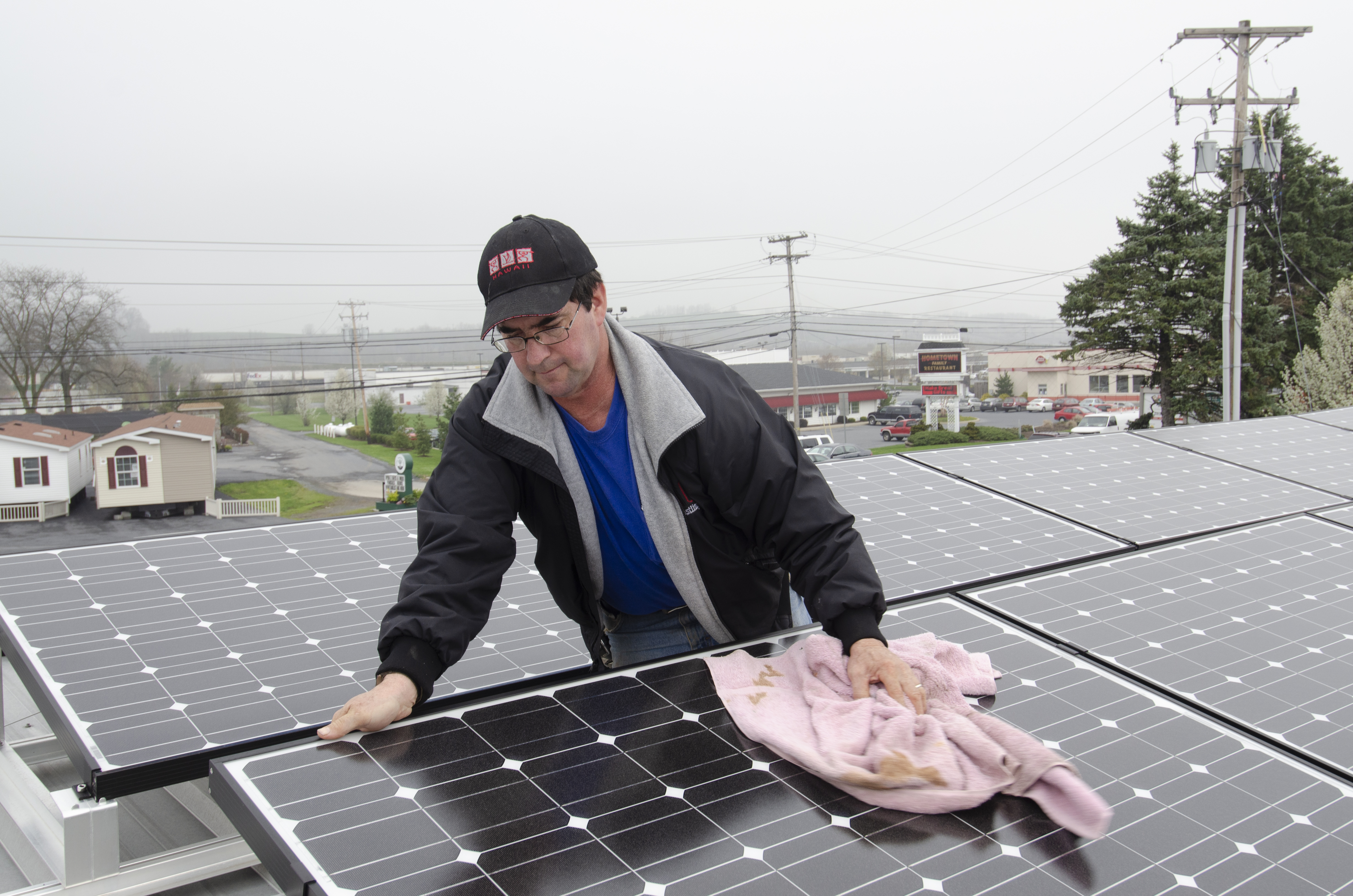 Technicien nettoyant des panneaux solaires photovoltaïques sur une toiture avec un chiffon